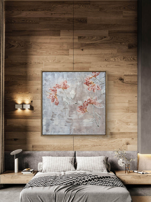 A framed floral wall art print with pink blossoms and pale blue-gray leaves, displayed above a bed in a modern bedroom with wood-paneled walls and bedside tables.